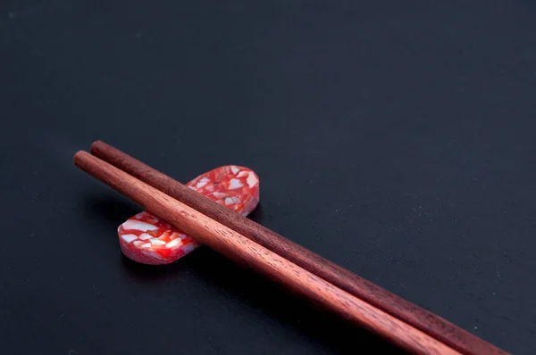 Ahşap çubuklar koyu arkaplanı olan renkli taşların üzerinde dururlar. Kapat..