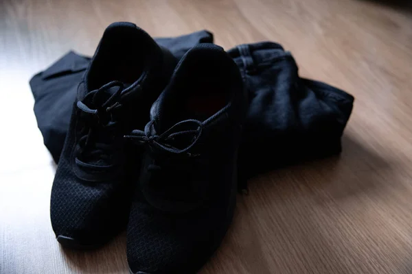 Νεκρή Φύση Μαύρα Αθλητικά Παπούτσια Και Μαύρα Ρούχα Ξύλινο Φόντο — Φωτογραφία Αρχείου