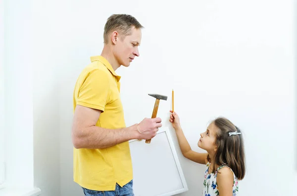 Father and daughter are deciding where the picture will hang.