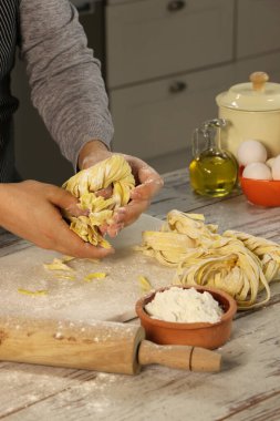 Erkek el, mutfak tezgahında hamur rulosu ve unla makarna yaparken görülüyor.