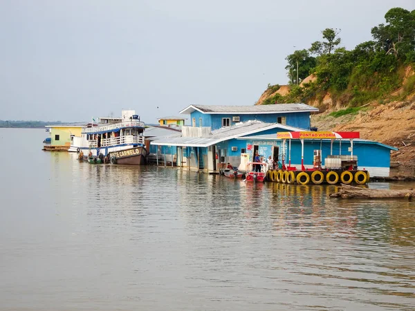 Wooden houses and a boat on a river bank, — Stock Photo, Image