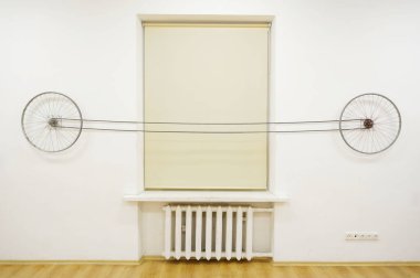 Duvarda bisiklet tekerlekleri, kişisel sanat ihtirası, galeri, pedal, konserve. Tekerlekler birbirine bağlıdır ve pedalı çevirerek tüm çarklar hareket eder. Evrendeki her şeyin birbirine bağlılığını temsil eder..