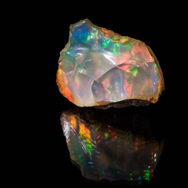 Kıymetli opal. Gemolojik örnek, kesik yok. Çok parlak, benzersiz bir örnek siyah bir arkaplanda yansıtılarak fotoğraflandı. Tek tedavi, tozun arka plandan çıkarılması..