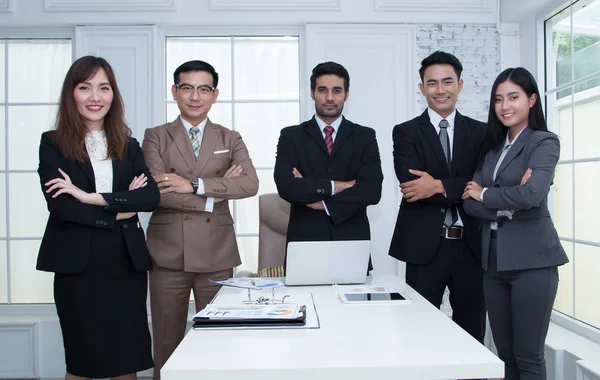 Kendine güvenen iş takım ayakta ve modern ofiste lo gülümseyen