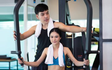 Genç bir kadın yardımcı yakışıklı kişisel fitness eğitmeni