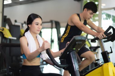 Çekici genç kadın ve genç adam spor salonunda, exercisi Bisiklet