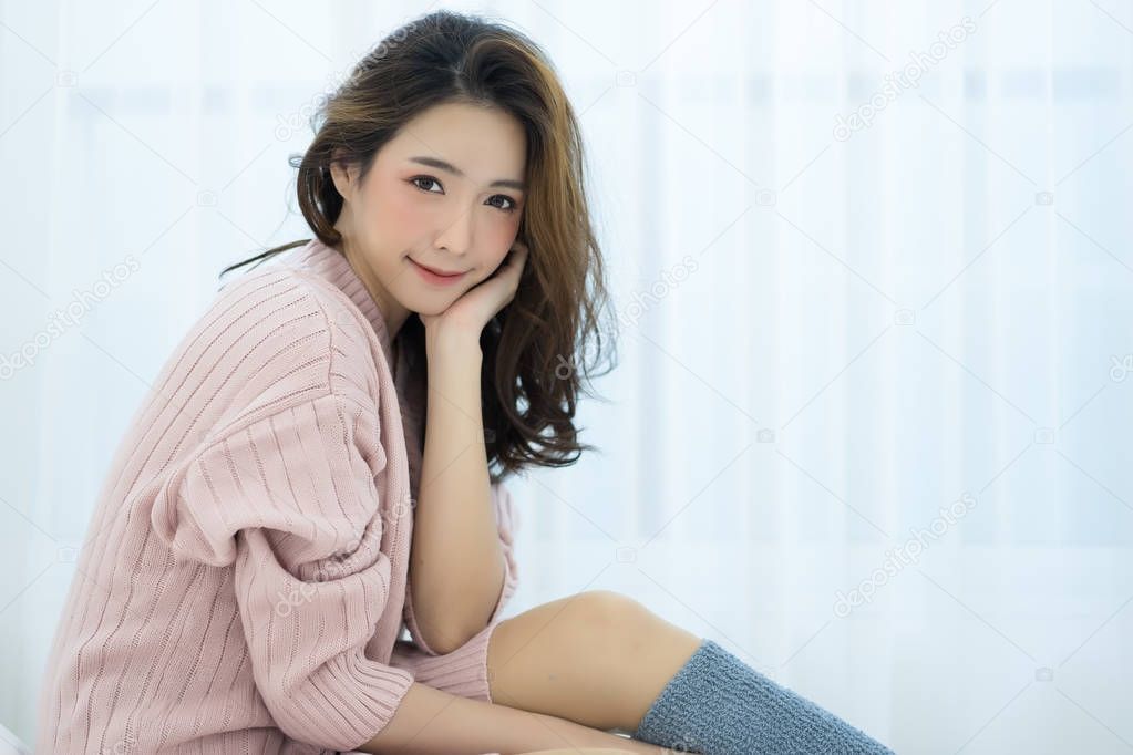 Beautiful Asian girl wearing sweater pink cold at home looking a