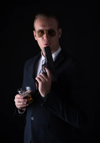 Portrait of handsome man in a suit with blowing on the barrel of — Stock Photo, Image