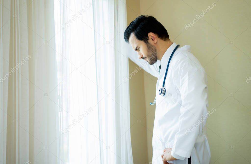 Thoughtful Handsome medical doctor looking out of medical office