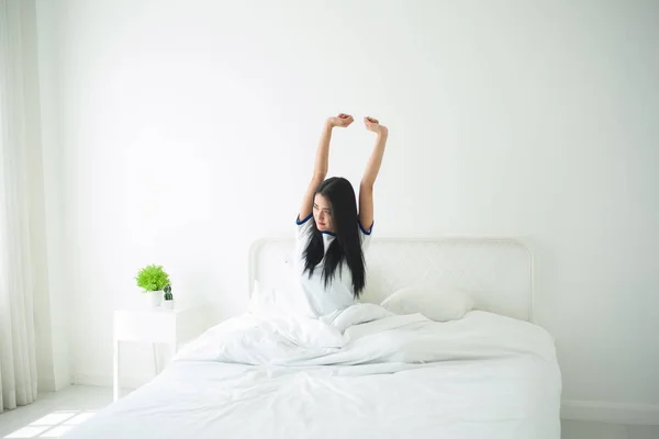 Schöne junge Frau wacht in ihrem Bett auf, sie dehnt sich — Stockfoto