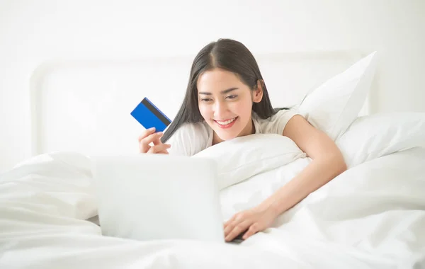 Счастливая женщина, использующая свою кредитку в Интернете, лежала и делала покупки. — стоковое фото