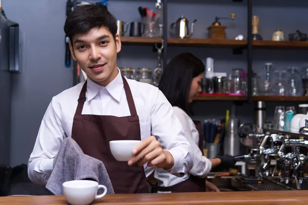 Portret van glimlachen barista schoonmaken kop koffie terwijl staand l — Stockfoto