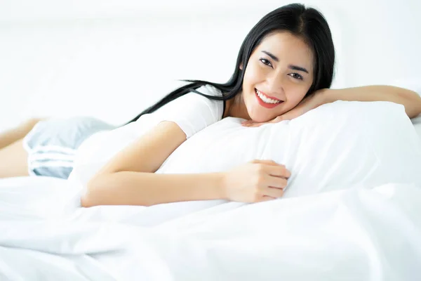 Attraente ragazza asiatica sdraiata su sfondo bianco a letto a casa — Foto Stock