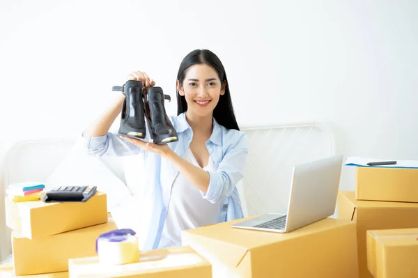 stock image Young business woman working small business online holding shoes