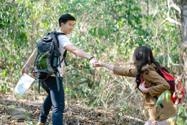 Fiatal ázsiai pár utazók kéz a kézben, ahogy az ember segít neki — Stock Fotó