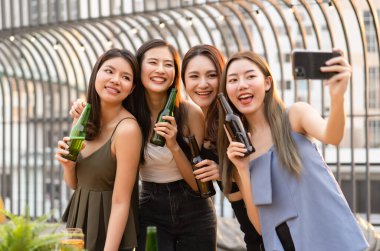 Bir grup Asyalı genç kız kendi portrelerini çekerek, dans ederek ve bir çatı partisinde içkilerle takılarak eğleniyor. Arkadaş sevgisi, parti, teknoloji, gece hayatı ve insan konsepti
