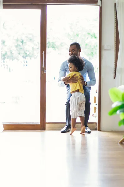 Happy family African American son running and hugging dad after going back from office. Welcome back home daddy and Sweet moments of fatherhood concept.