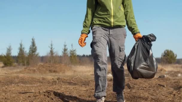 Jambes d'un volontaire portant un sac dans ses mains — Video