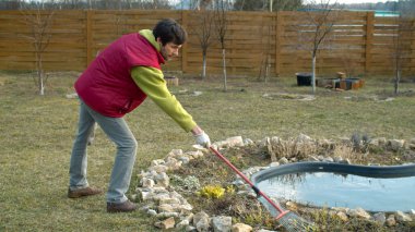 Bahçede bahar işi. Genç adam geçen yıl çiçek tarlasında çim biçiyordu. Çevre dostu. Dünya günü.
