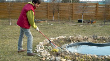 Bahçede bahar işi. Genç adam geçen yıl çiçek tarlasında çim biçiyordu. Çevre dostu. Dünya günü.
