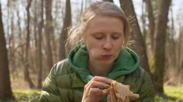 Trevlig kvinna äter sanwich i skogen — Stockvideo