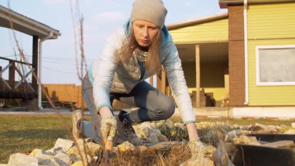 Jonge vrouw harken droog gras — Stockvideo