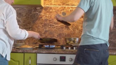 Anne ve oğul krep kızartıyorlar.