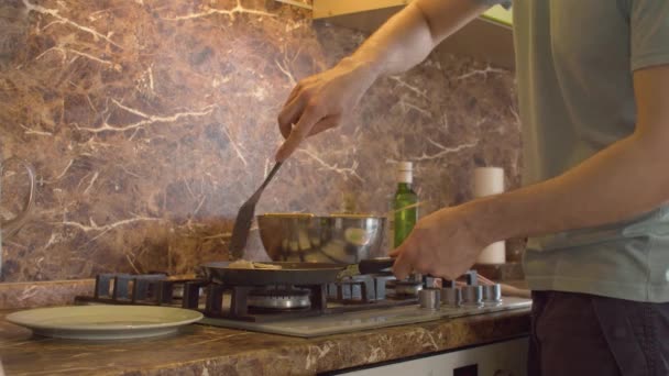 Чоловік бере липкий млинчик з сковороди — стокове відео