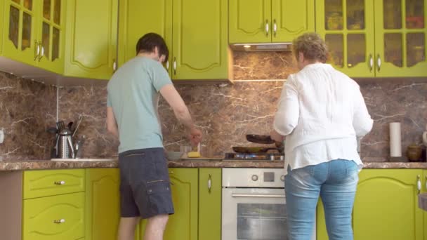 Mãe sênior e filho adulto fritando panquecas — Vídeo de Stock