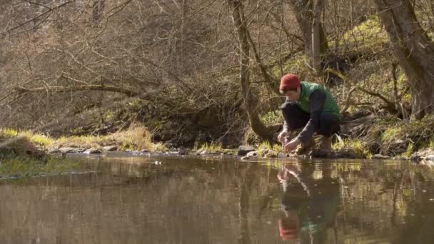 Joven lava los platos en un río del bosque — Vídeo de stock