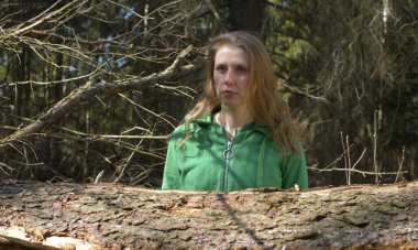 Ormanda poz veren güzel bir kadının portresi. Saçlarını arkaya atar ve gülümser. Baharın ilk günleri, güneşli havalar, çıplak ağaçlar. Sağlıklı yaşam tarzı kavramı