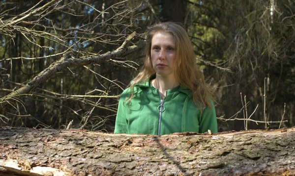 Ormanda poz veren güzel bir kadının portresi. Saçlarını arkaya atar ve gülümser. Baharın ilk günleri, güneşli havalar, çıplak ağaçlar. Sağlıklı yaşam tarzı kavramı