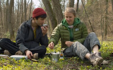 Genç bir aile, İtalyan espresso makinesinde ormanda kahve pişiriyor. Bir adam kahve kokluyor.