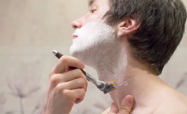 用剃须机在肥皂泡剃须刀刮脸刮颈的特写镜头 日常面部护理 图库图片