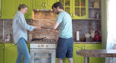 Genç bir aile blini hazırlıyor. Koca, hamurla kasede yumurta kırıyor, karısı da ona yardım ediyor. Krep tavası ateşte ısıtılır. Ev hayatı, yemek pişirme.