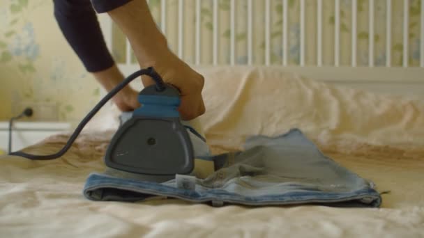 Manos masculinas planchando jeans en la cama — Vídeos de Stock