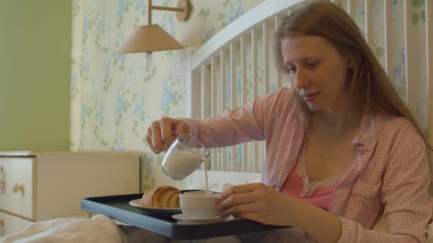 Молода жінка снідає в ліжку — стокове відео