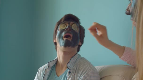 Забавна людина в чорній масці для пілінгу їсть огірок — стокове відео