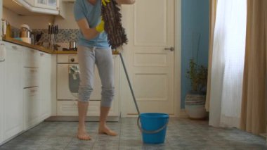 Komik adam yerleri paspasla yıkıyor.