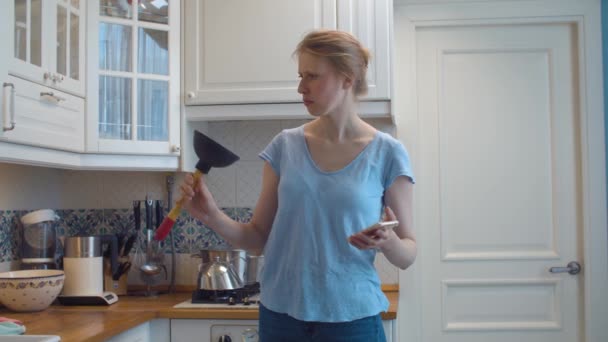 Zdezorientowana kobieta w kuchni z przepychaczem w rękach — Wideo stockowe