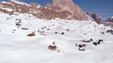 İtalyan Dolomitleri, Val Gardena, Güney Tyrol, İtalya, Avrupa 'da güneşli bir günde, kışın çok güzel dağ arka planına sahip bir şapelin havadan 4k görüntüsü.