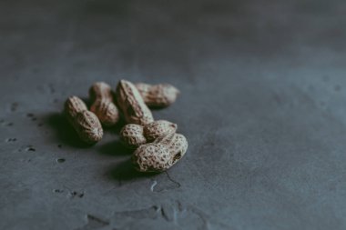 Soyulmamış, kabuklu, beton mavisi arka planda kurutulmuş fıstıklardan oluşan bir grubun yakın çekimi. Mutfak ve konsept. Uzayı kopyala Yumuşak odaklanma. Doğal arkaplan