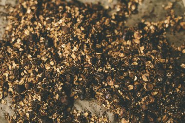 Ev yapımı çikolatalı granola fırında. Fındık dilimleri ve kuru meyveli yulaf ezmesi. Makro sıcak kahverengi tonlarda çekilir..