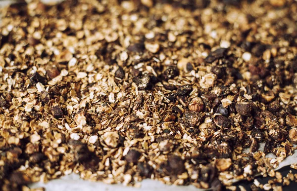 Ev yapımı çikolatalı granola fırında. Fındık dilimleri ve kuru meyveli yulaf ezmesi. Makro sıcak kahverengi tonlarda çekilir..