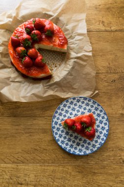 Çilekli ev yapımı cheesecake ve ahşap bir masada pasta.