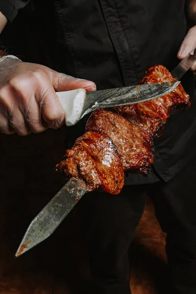 Aşçının elindeki şişte altın hamuru olan sulu bir kebap. Hazır kuzu kebabı şişten keskin bir bıçakla çıkarılır..