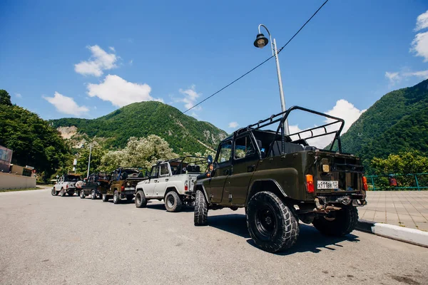Bir yaz günü bir grup SUV aracını güzel dağların arka planına park etmek. Yolun dışındaki açık havada Jeep maceraları. Off-road araba gezisi..