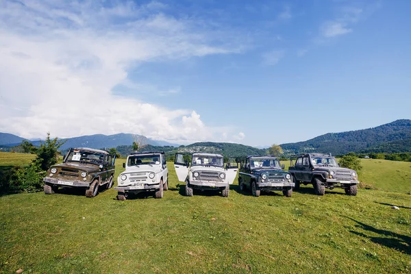 Bir yaz günü bir grup SUV aracını güzel dağların arka planına park etmek. Yolun dışındaki açık havada Jeep maceraları. Off-road araba gezisi..