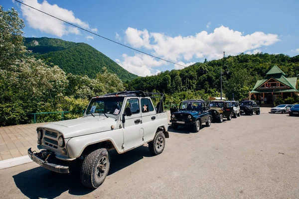 Bir yaz günü bir grup SUV aracını güzel dağların arka planına park etmek. Yolun dışındaki açık havada Jeep maceraları. Off-road araba gezisi..