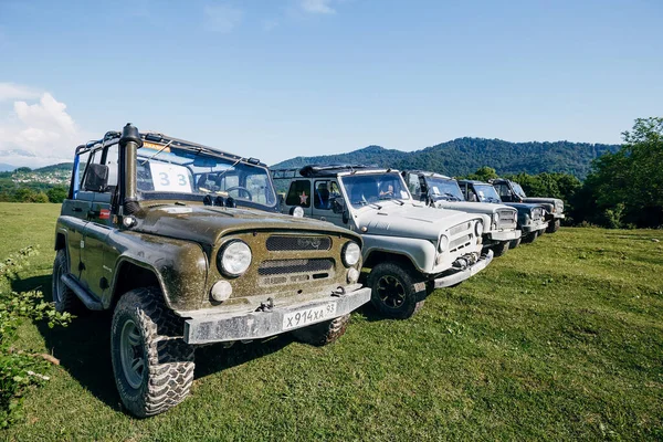 Bir yaz günü bir grup SUV aracını güzel dağların arka planına park etmek. Yolun dışındaki açık havada Jeep maceraları. Off-road araba gezisi..